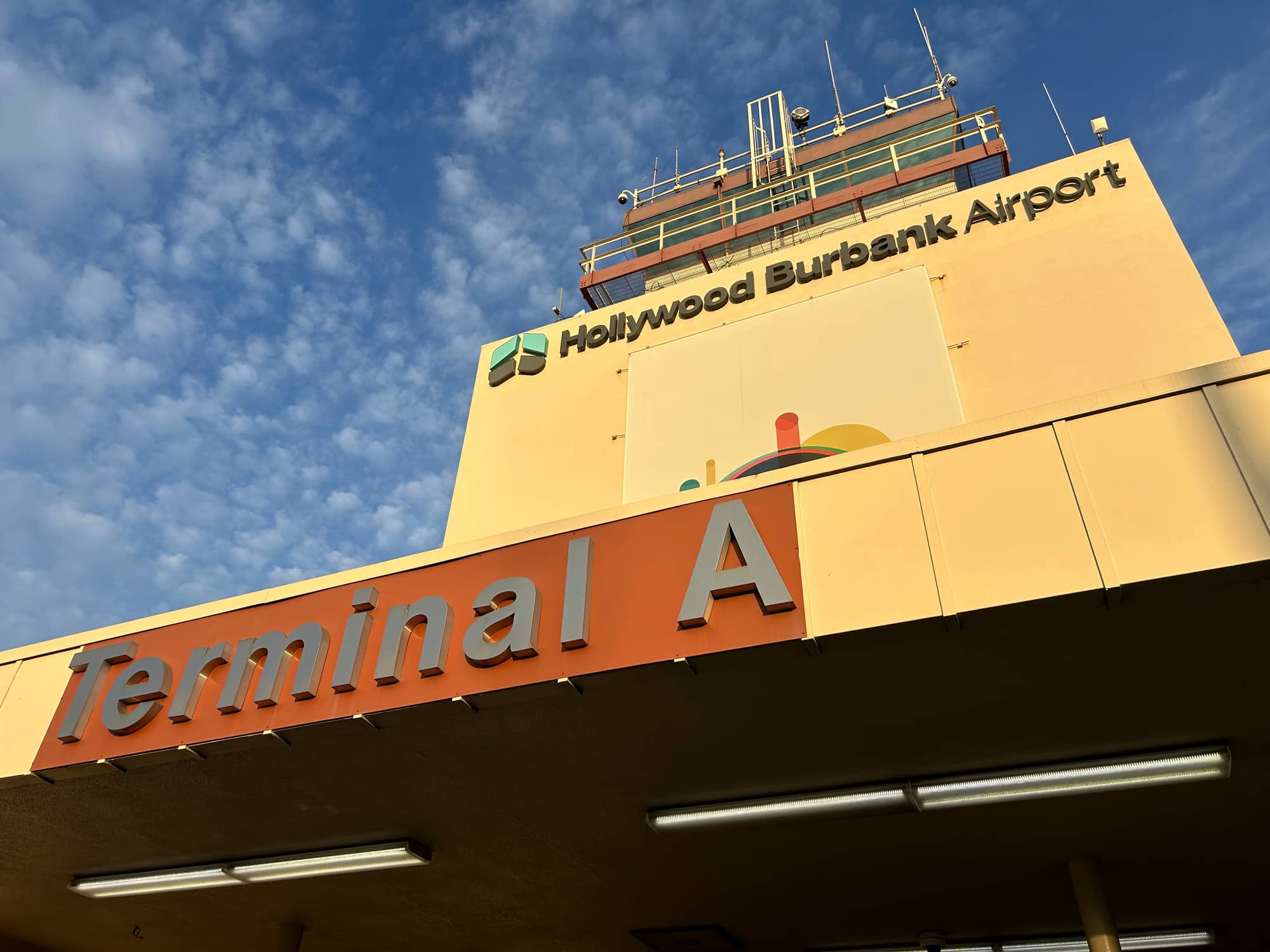 The Terminal A sign and the control tower of the old Hollywood Burbank Airport terminal against a blue sky in February 2026