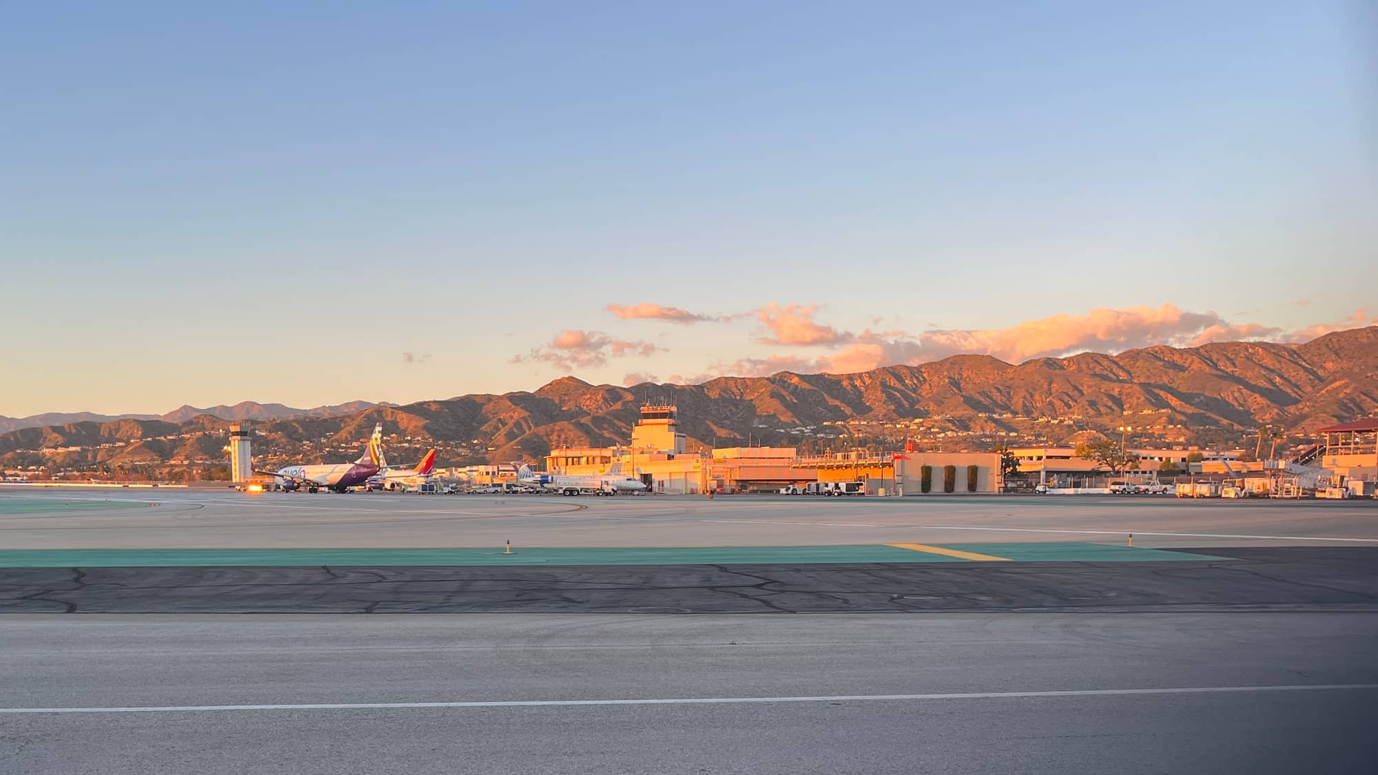 Hollywood Burbank Airport at sunset in February 2022, with aircraft parked at the old terminal and the Verdugo Mountains behind