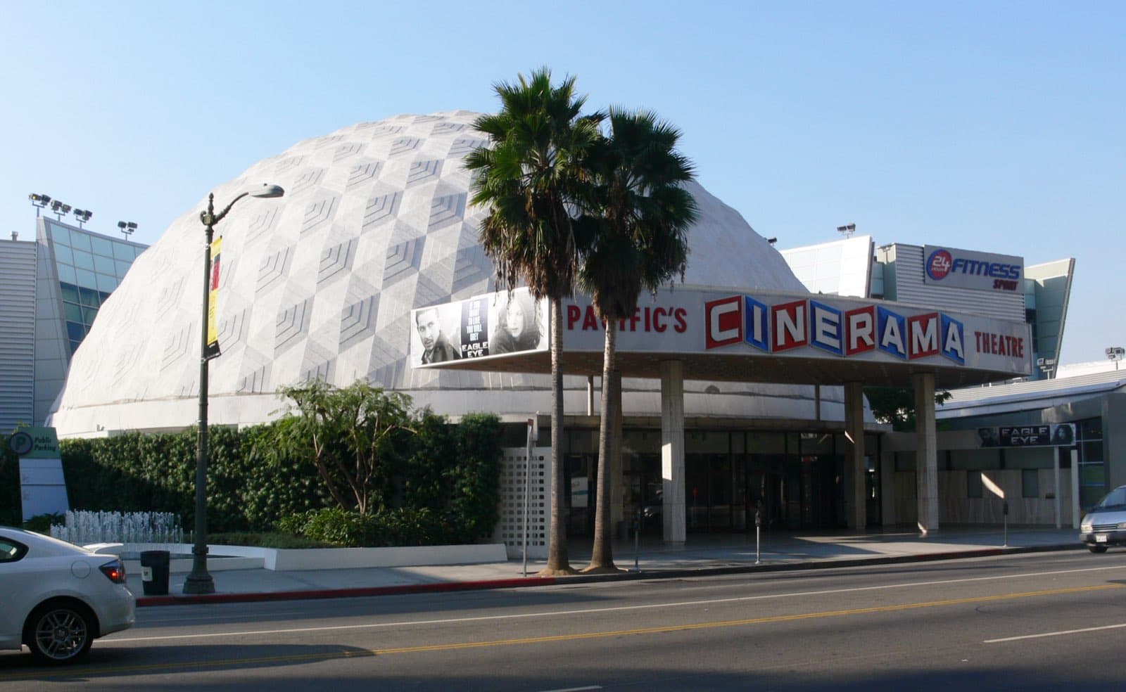 The Cinerama Dome seen from across Sunset Boulevard, its geodesic concrete panels catching the sun above the flat entrance canopy and palm trees