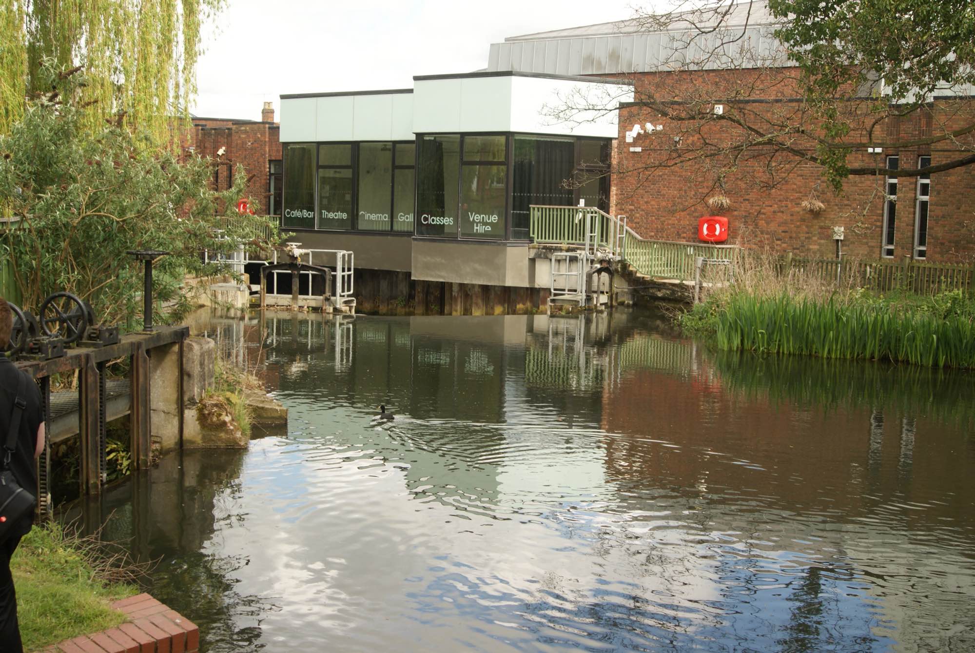 The Hertford Theatre across the River Lea in 2015, a flat-roofed building with a glazed upper storey, before its conversion into BEAM
