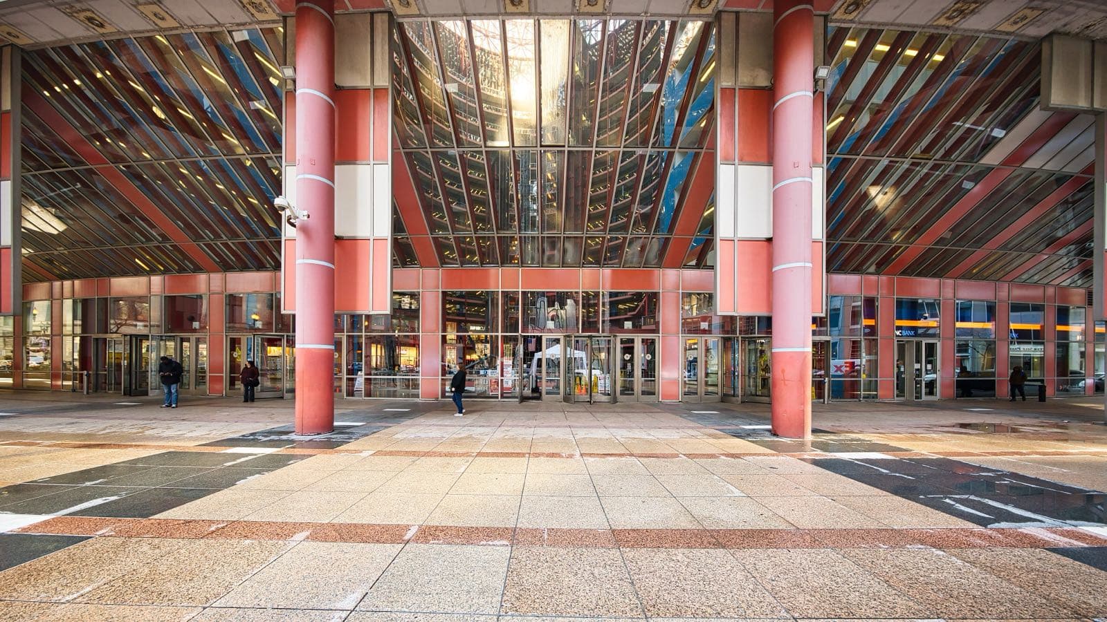 Two salmon-coloured columns frame the glass doors of the Thompson Center's plaza entrance under a raking glazed canopy