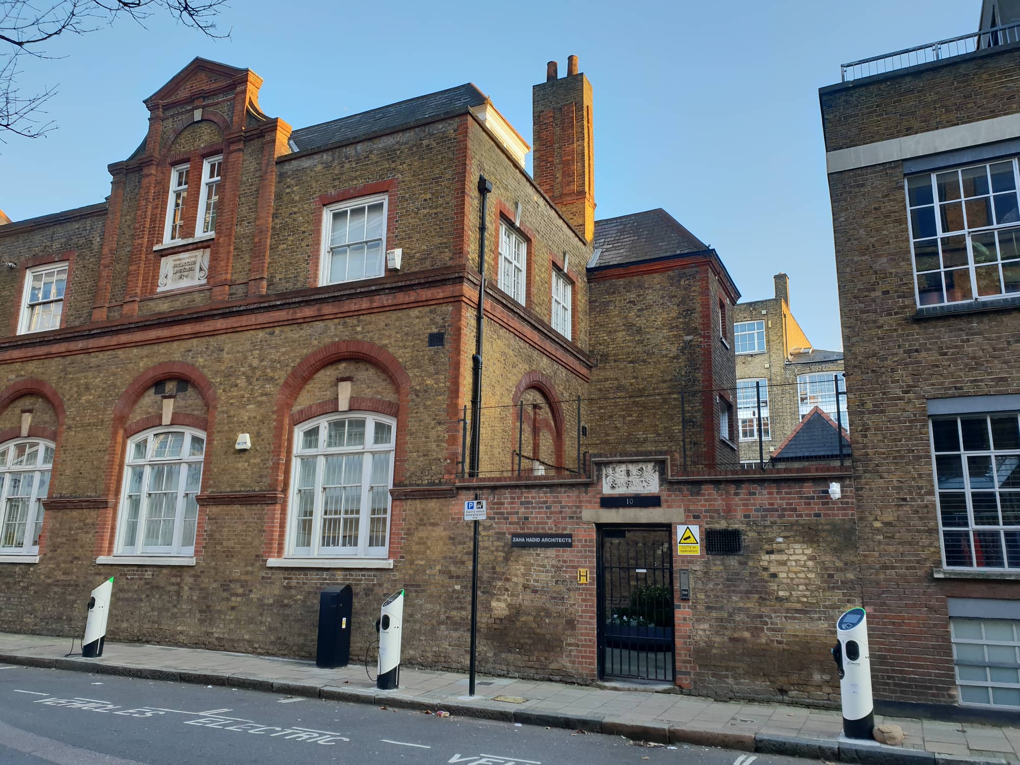 The Zaha Hadid Foundation's building at 10 Bowling Green Lane, Clerkenwell: a Victorian school in yellow stock brick with red brick arches, a gated doorway and a Zaha Hadid Architects nameplate